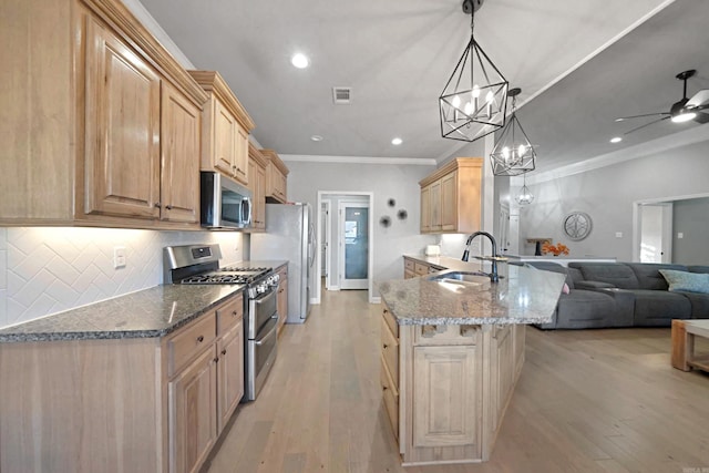 kitchen with light brown cabinets, sink, hanging light fixtures, kitchen peninsula, and stainless steel appliances