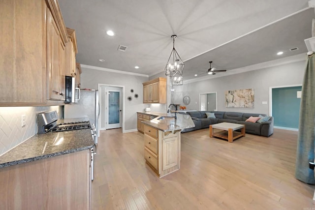 kitchen with light brown cabinetry, tasteful backsplash, gas stove, sink, and pendant lighting