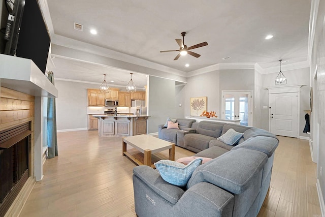 living room with french doors, ceiling fan with notable chandelier, light hardwood / wood-style floors, and crown molding