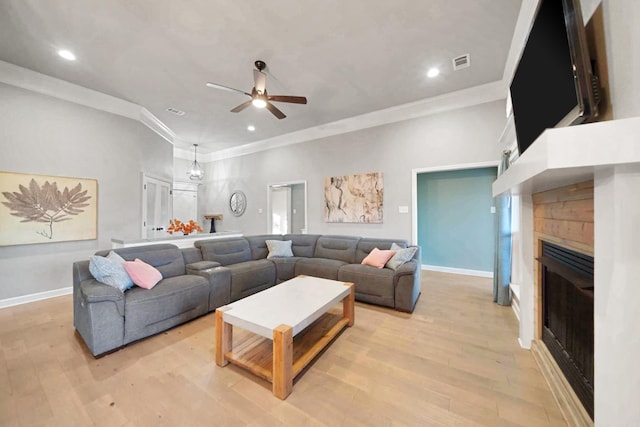 living room with ceiling fan, light wood-type flooring, ornamental molding, and a fireplace