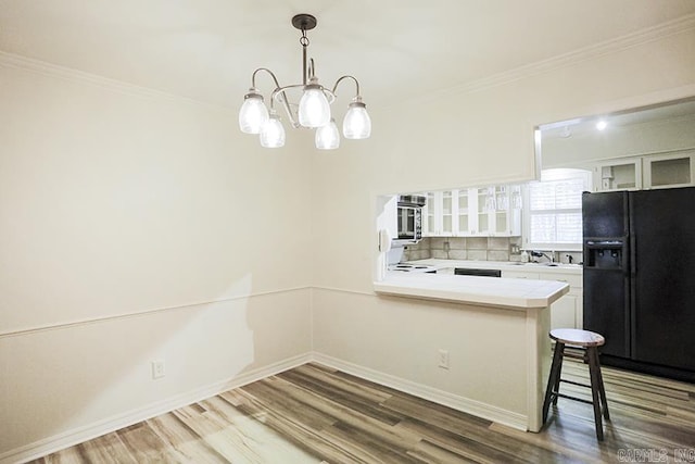 kitchen featuring kitchen peninsula, black fridge with ice dispenser, decorative light fixtures, a notable chandelier, and white cabinetry