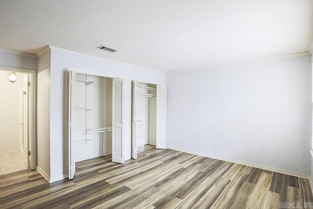 unfurnished bedroom featuring crown molding and dark hardwood / wood-style flooring