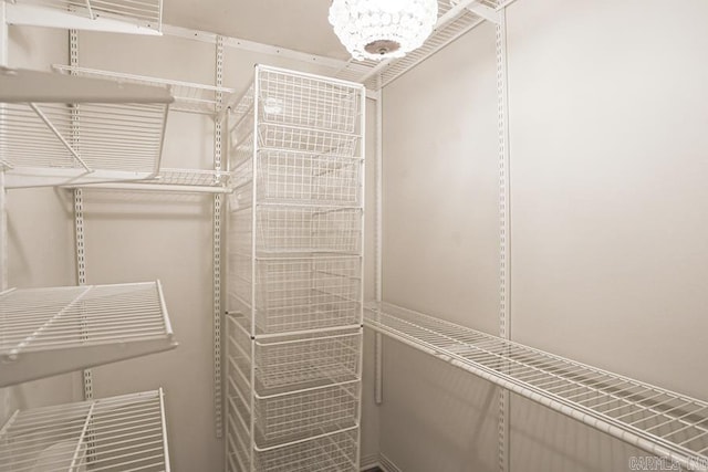 walk in closet with a notable chandelier