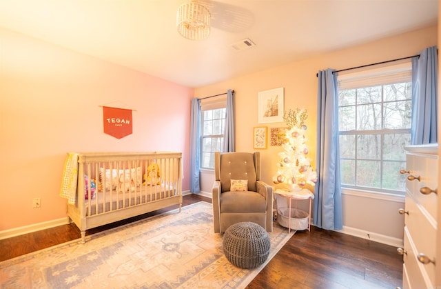 bedroom featuring dark hardwood / wood-style flooring and a crib