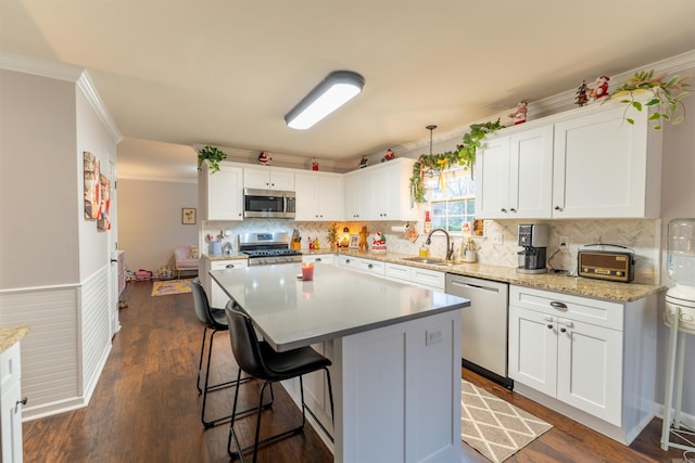 kitchen featuring pendant lighting, white cabinets, sink, appliances with stainless steel finishes, and a kitchen island