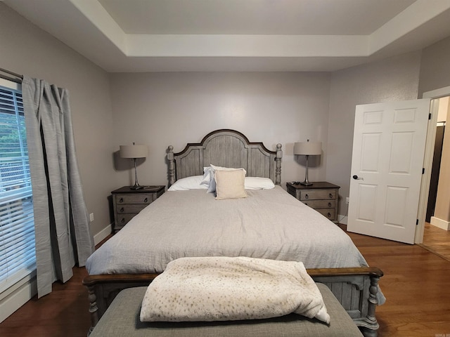 bedroom featuring dark hardwood / wood-style floors and a tray ceiling