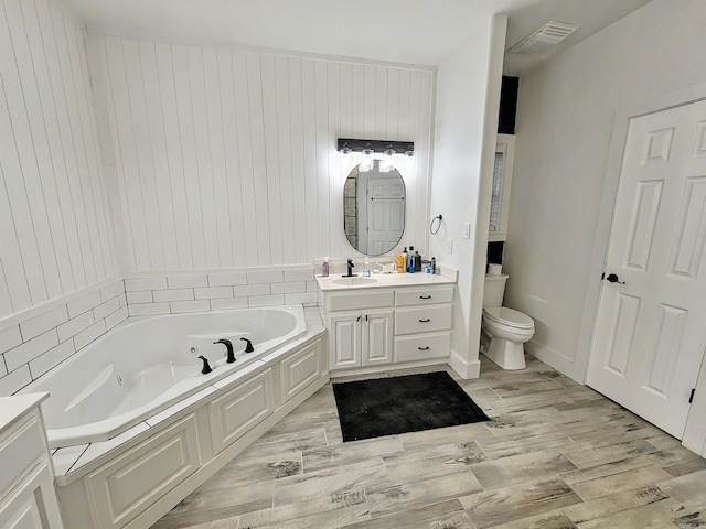 bathroom with hardwood / wood-style floors, vanity, toilet, and a tub