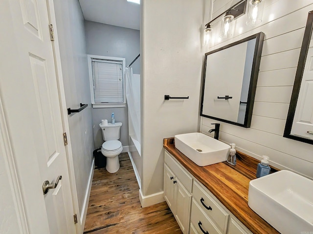 full bathroom featuring vanity, hardwood / wood-style flooring, washtub / shower combination, and toilet