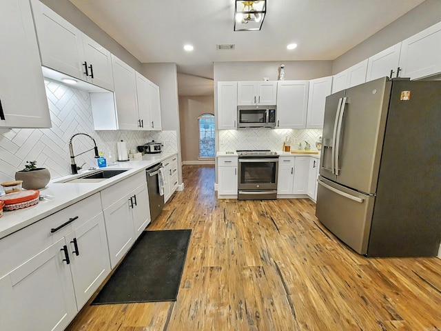 kitchen with light hardwood / wood-style flooring, stainless steel appliances, white cabinetry, and sink