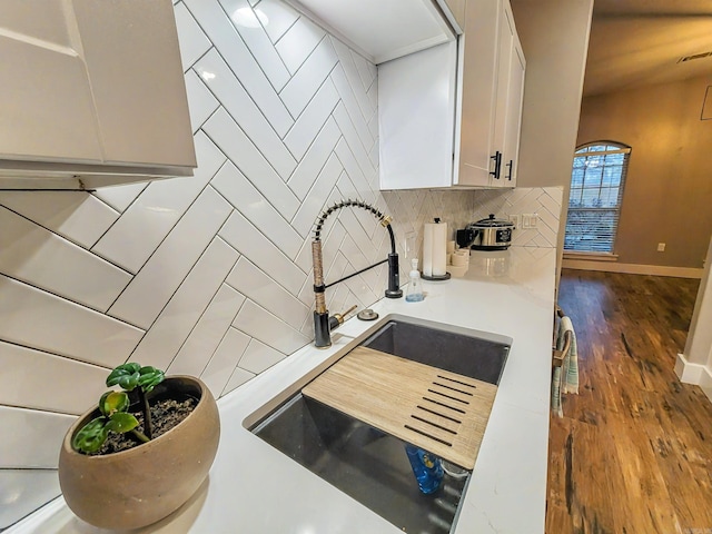 kitchen with decorative backsplash, white cabinetry, sink, and dark wood-type flooring