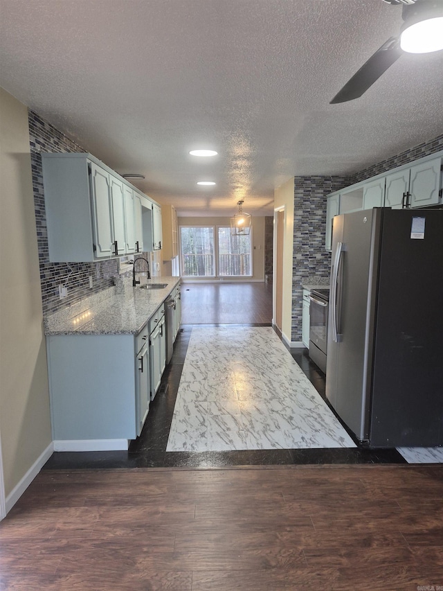 kitchen featuring ceiling fan, sink, a textured ceiling, decorative backsplash, and appliances with stainless steel finishes