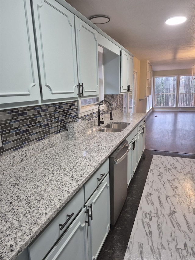 kitchen with tasteful backsplash, light stone counters, sink, dishwasher, and white cabinetry