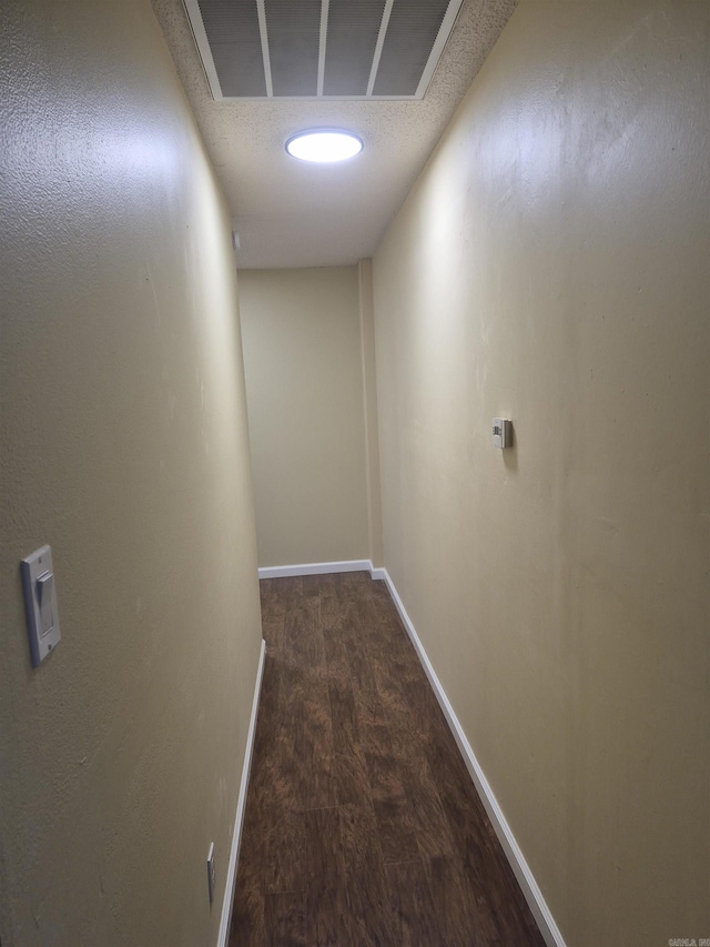 corridor featuring a textured ceiling and dark hardwood / wood-style floors