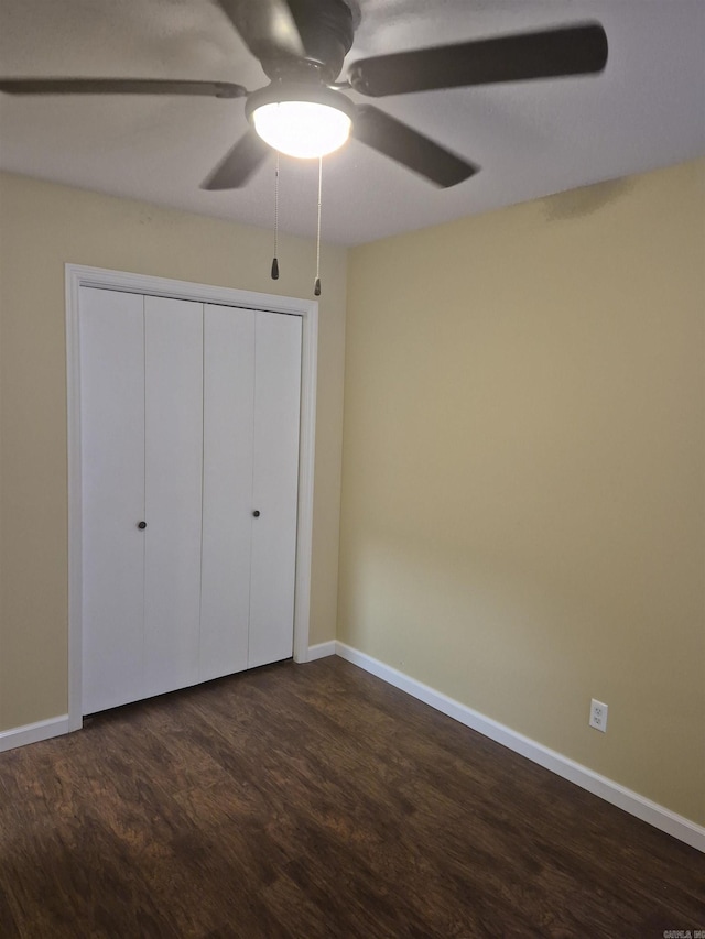 unfurnished bedroom featuring ceiling fan, dark hardwood / wood-style floors, and a closet