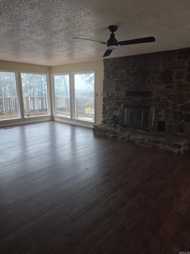 unfurnished living room with dark hardwood / wood-style floors, a stone fireplace, and ceiling fan