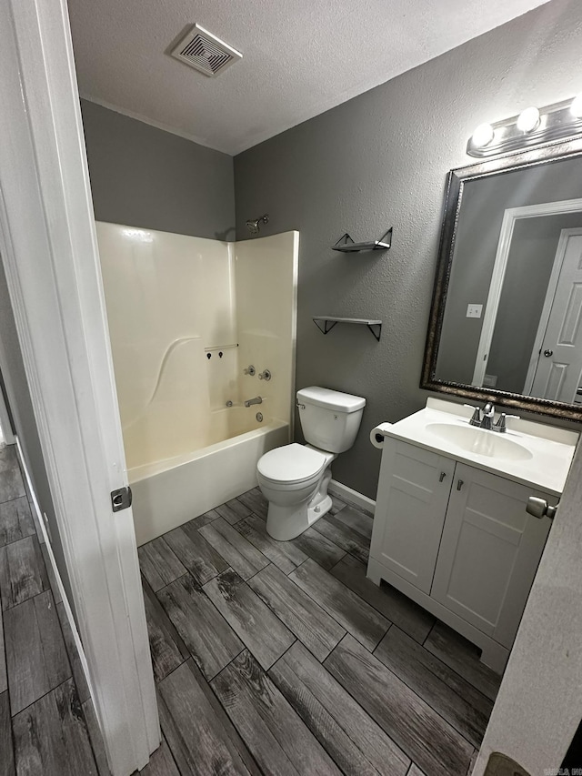 full bathroom featuring toilet, vanity, a textured ceiling, and tub / shower combination