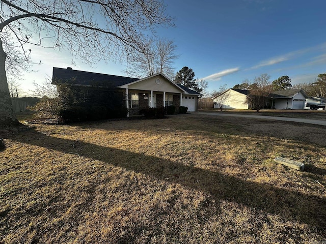 single story home featuring a front yard, a porch, and a garage