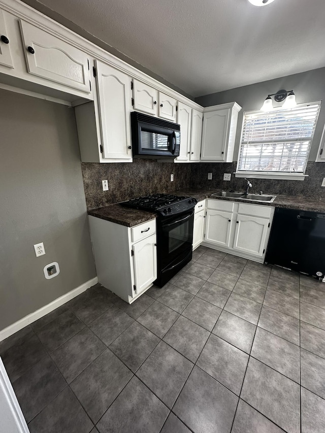 kitchen with white cabinetry, sink, tasteful backsplash, dark tile patterned floors, and black appliances