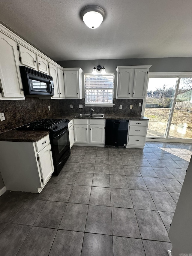 kitchen featuring tasteful backsplash, sink, black appliances, dark tile patterned flooring, and white cabinets