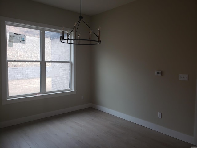 unfurnished dining area featuring wood-type flooring and an inviting chandelier