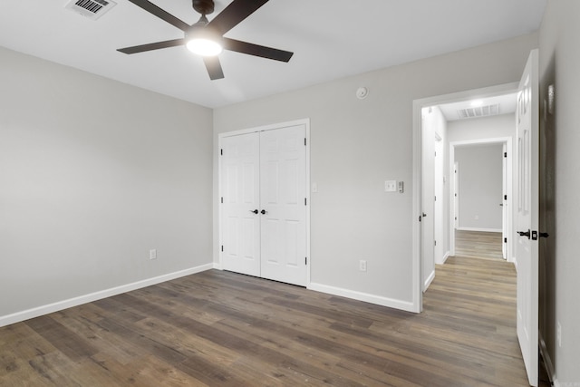 unfurnished bedroom with ceiling fan, dark hardwood / wood-style floors, and a closet