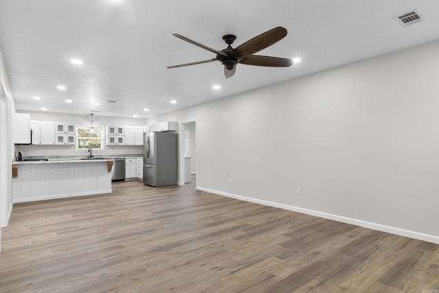 unfurnished living room with ceiling fan, light wood-type flooring, and sink