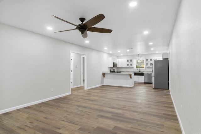 unfurnished living room with dark hardwood / wood-style floors, ceiling fan, and sink