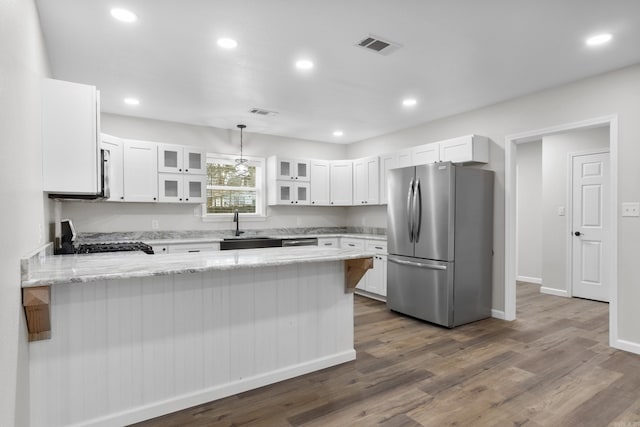 kitchen with stainless steel refrigerator, white cabinetry, kitchen peninsula, and pendant lighting