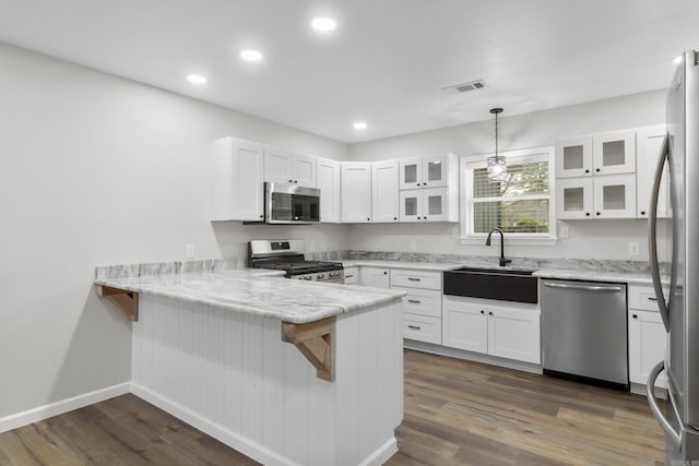 kitchen featuring pendant lighting, white cabinets, sink, kitchen peninsula, and stainless steel appliances