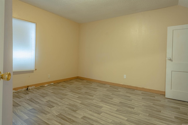 empty room featuring a textured ceiling and light hardwood / wood-style flooring