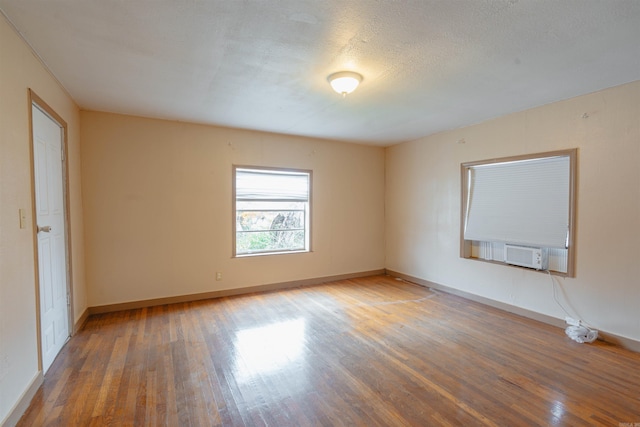 empty room with cooling unit, wood-type flooring, and a textured ceiling