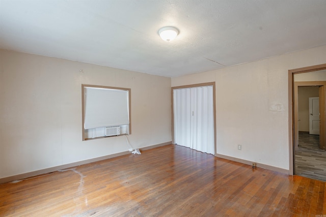 unfurnished bedroom featuring a textured ceiling, hardwood / wood-style flooring, and cooling unit