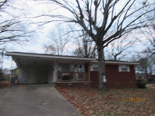 ranch-style house featuring covered porch and a carport