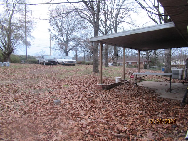 view of yard with central AC unit and a carport