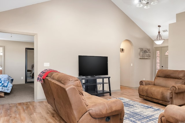 living room with light hardwood / wood-style floors and high vaulted ceiling