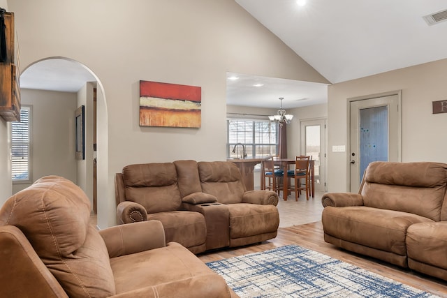 living room with sink, high vaulted ceiling, a chandelier, and light wood-type flooring