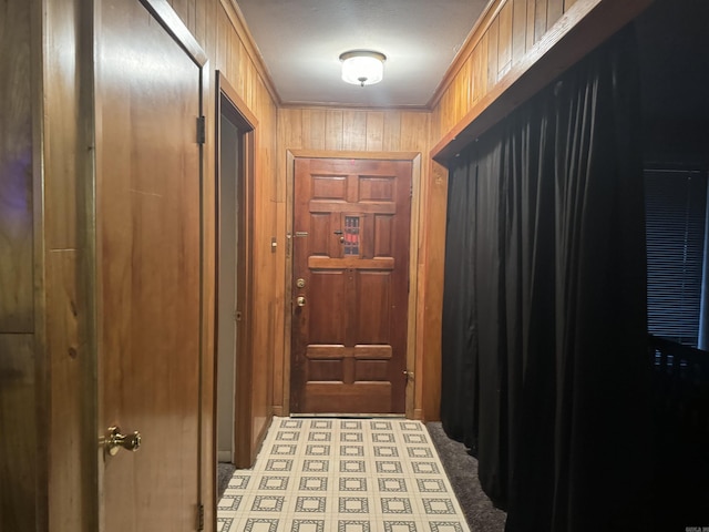 doorway with crown molding and wood walls