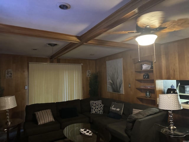 living room featuring built in shelves, beam ceiling, coffered ceiling, and wood walls