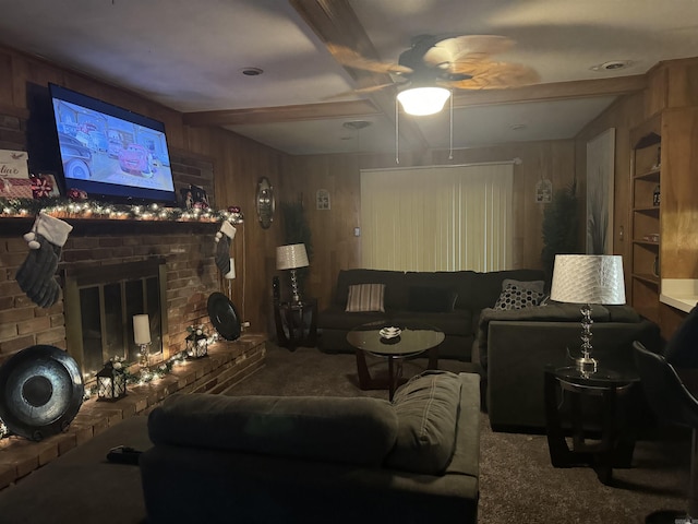 living room featuring wood walls, a brick fireplace, built in shelves, ceiling fan, and beamed ceiling