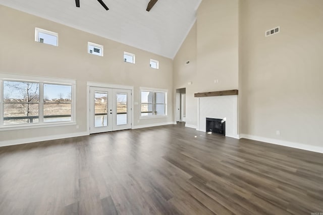 unfurnished living room with french doors, a wealth of natural light, ceiling fan, and a high ceiling