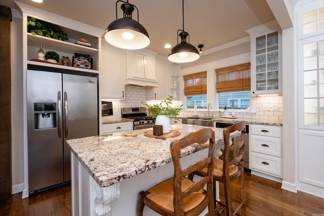 kitchen featuring pendant lighting, white cabinetry, premium range hood, and appliances with stainless steel finishes