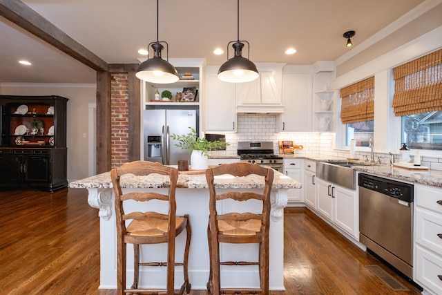 kitchen with a center island, white cabinets, a kitchen breakfast bar, light stone counters, and stainless steel appliances