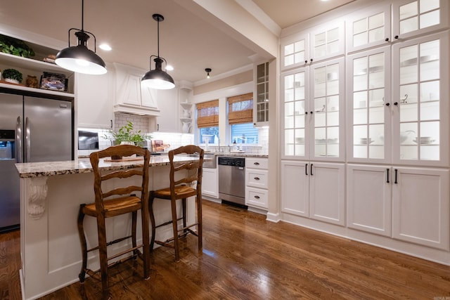 kitchen with white cabinets, appliances with stainless steel finishes, light stone countertops, and hanging light fixtures