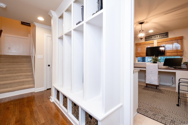 mudroom featuring hardwood / wood-style flooring, built in desk, and an inviting chandelier