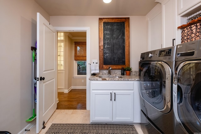 laundry area featuring cabinets, light tile patterned floors, washing machine and dryer, and sink