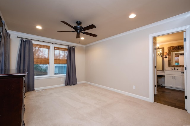 unfurnished bedroom featuring light carpet, ensuite bathroom, ceiling fan, crown molding, and sink