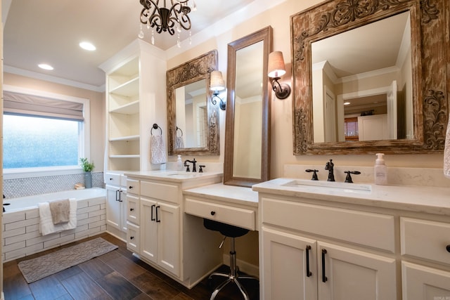 bathroom featuring tiled bath, crown molding, vanity, and an inviting chandelier