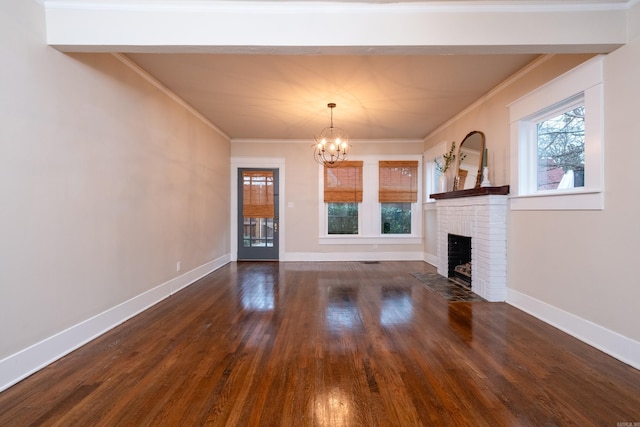 unfurnished living room featuring crown molding, dark hardwood / wood-style flooring, a chandelier, and a brick fireplace