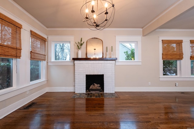 unfurnished living room featuring a brick fireplace, dark hardwood / wood-style flooring, crown molding, and an inviting chandelier