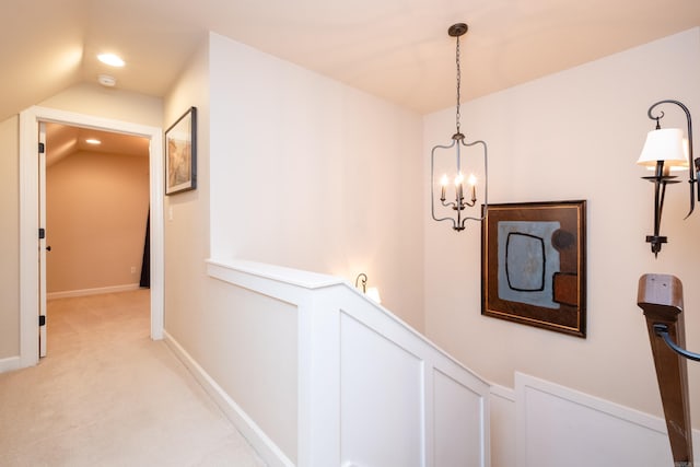 corridor featuring a chandelier, light carpet, and vaulted ceiling